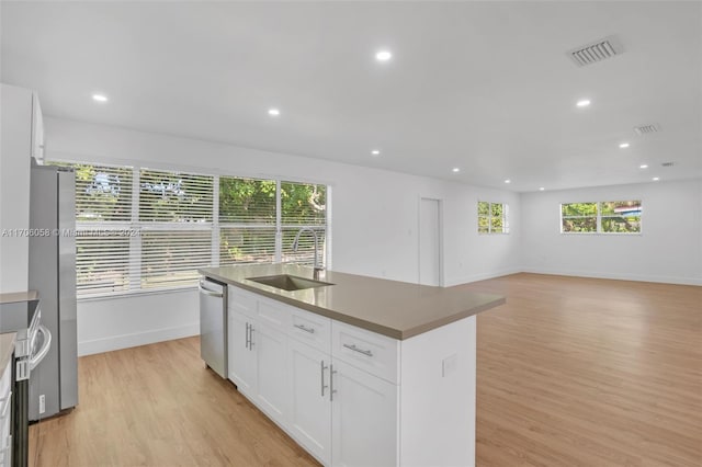 kitchen featuring white cabinetry, sink, a kitchen island with sink, appliances with stainless steel finishes, and light wood-type flooring