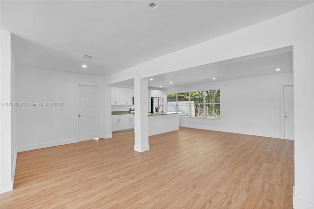 unfurnished living room featuring light wood-type flooring and sink