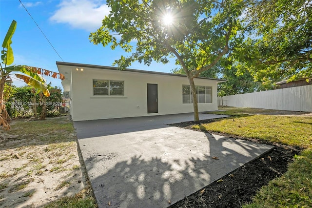 back of property with a yard and a patio