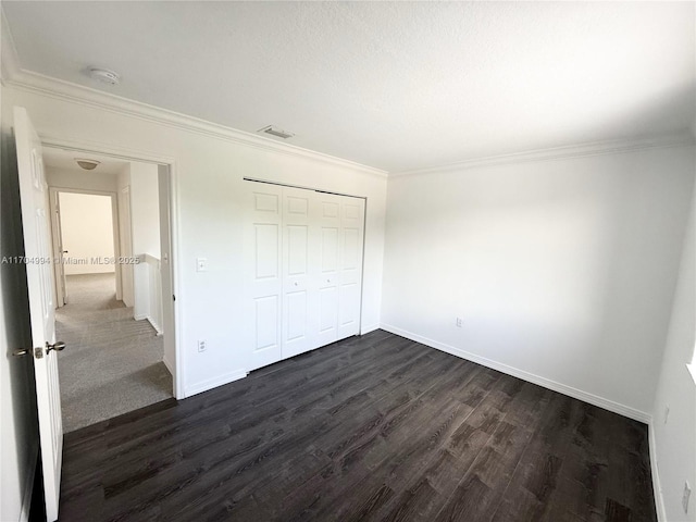 unfurnished bedroom with a closet, dark hardwood / wood-style floors, and ornamental molding