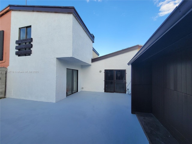 rear view of property with a patio and stucco siding