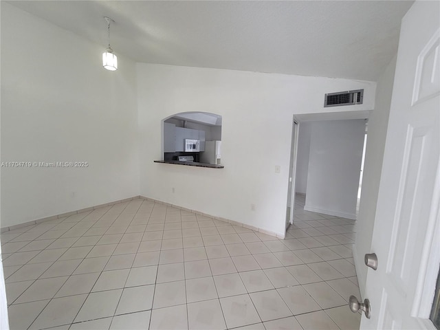 unfurnished room with lofted ceiling, light tile patterned floors, visible vents, and arched walkways