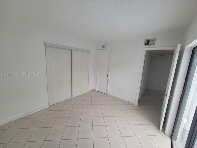 unfurnished bedroom with light tile patterned floors, a textured ceiling, and a closet