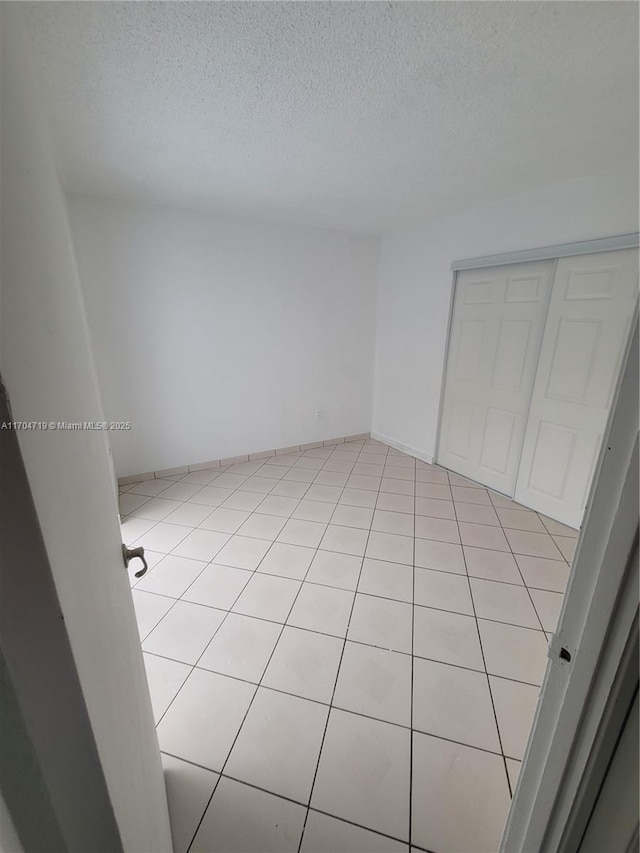 spare room featuring a textured ceiling and light tile patterned floors