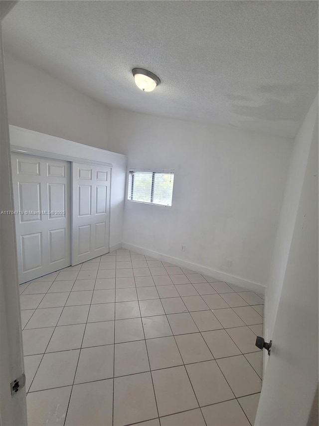 unfurnished bedroom featuring a textured ceiling, a closet, and baseboards