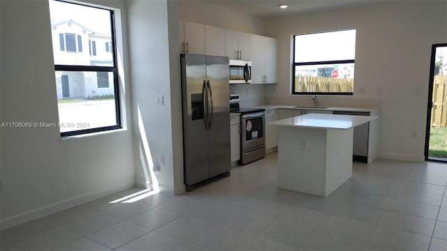 kitchen featuring white cabinetry, sink, light tile patterned floors, a kitchen island, and appliances with stainless steel finishes