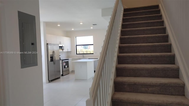 stairway featuring electric panel and sink