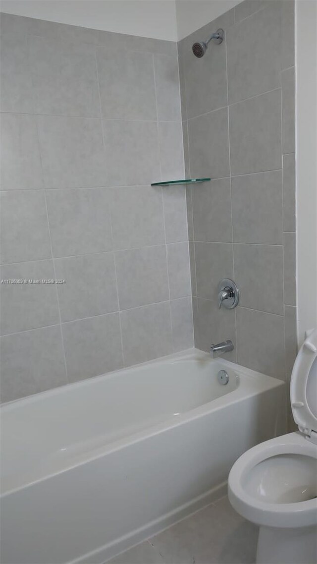 bathroom with tile patterned floors, tiled shower / bath combo, and toilet