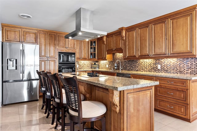 kitchen featuring island exhaust hood, light stone counters, black appliances, a kitchen island, and light tile patterned flooring