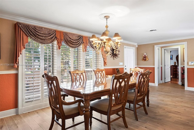 dining room featuring light wood-type flooring, an inviting chandelier, and ornamental molding