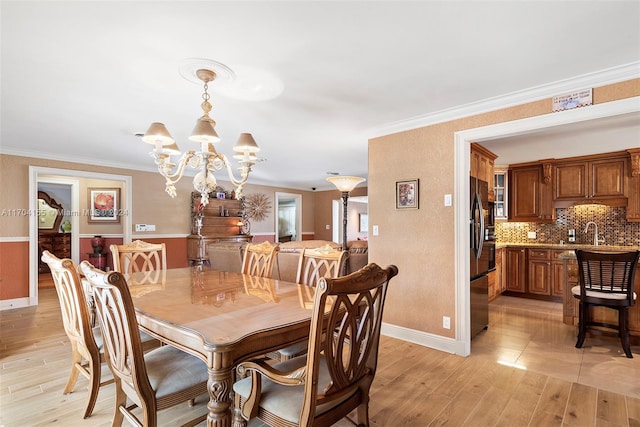 dining room with a chandelier, crown molding, light hardwood / wood-style floors, and sink