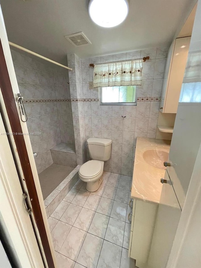 bathroom featuring tile patterned floors, vanity, toilet, and tile walls