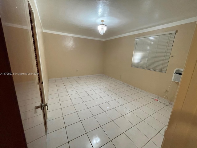 empty room with light tile patterned floors, an AC wall unit, and ornamental molding