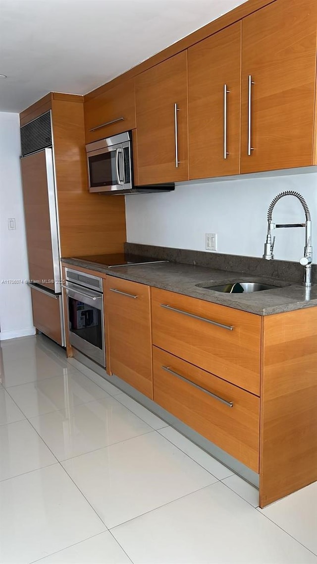 465 Brickell Ave Unit 4004, Miami, FL 33131 - kitchen featuring appliances with stainless steel finishes, dark countertops, brown cabinetry, and modern cabinets