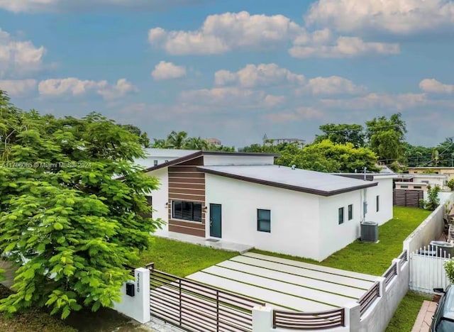 rear view of property featuring a lawn and central AC unit