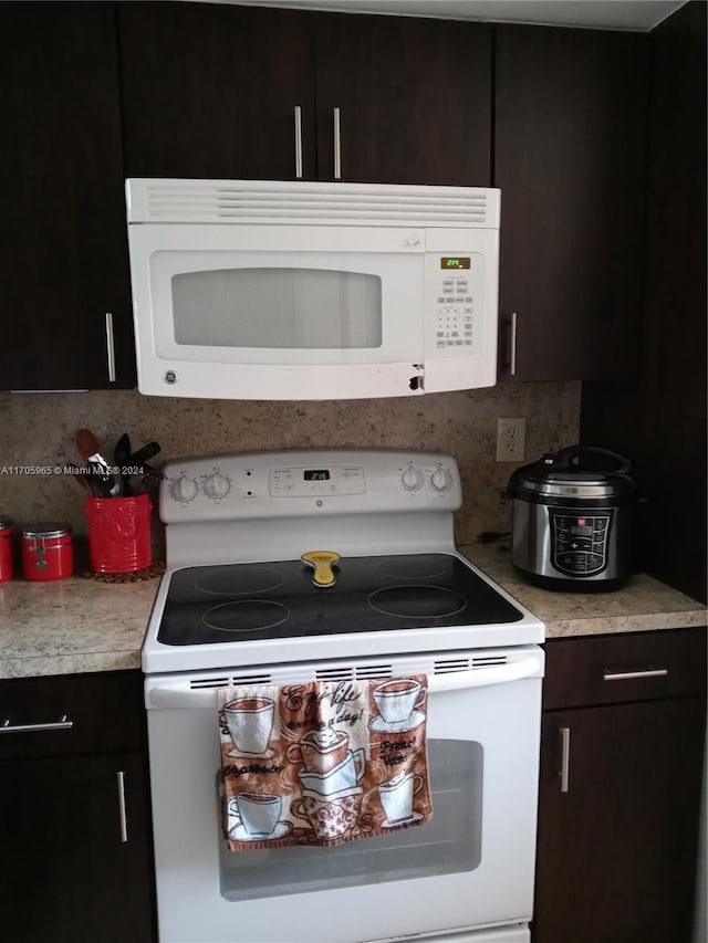 kitchen with dark brown cabinets, white appliances, and tasteful backsplash