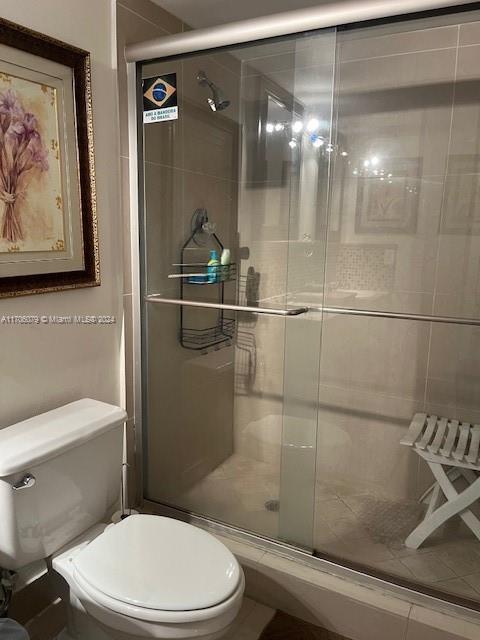 bathroom featuring a shower with shower door and toilet