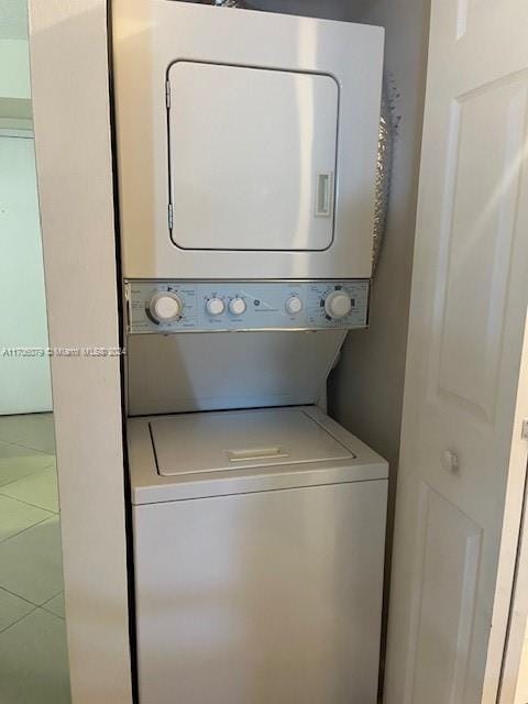 clothes washing area with tile patterned floors and stacked washer / drying machine