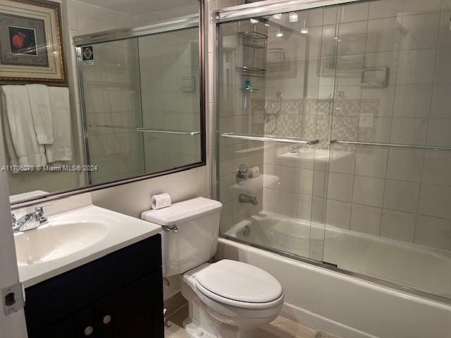 full bathroom featuring vanity, toilet, and combined bath / shower with glass door