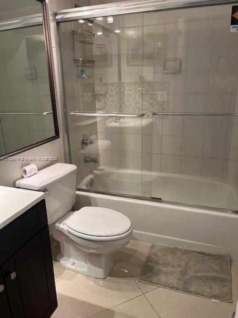 full bathroom featuring tile patterned floors, vanity, toilet, and enclosed tub / shower combo