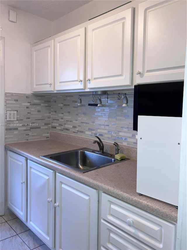 kitchen with tasteful backsplash, sink, white cabinets, and hanging light fixtures