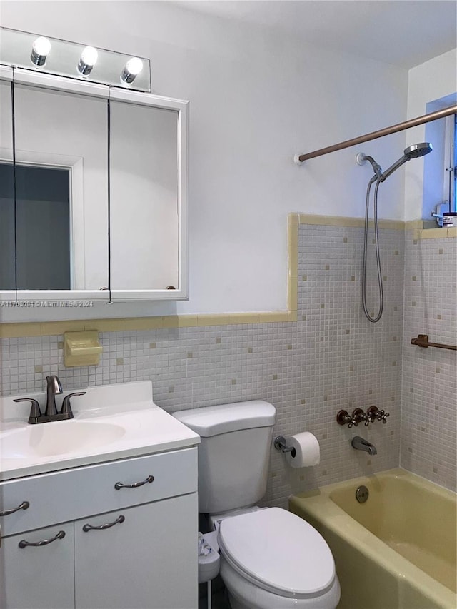 full bathroom featuring tile walls, vanity, tiled shower / bath combo, and toilet