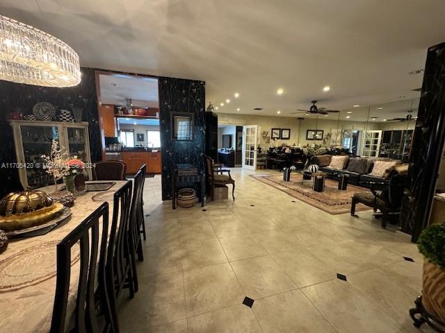 tiled dining area with ceiling fan with notable chandelier