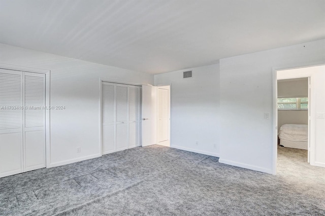 unfurnished bedroom with multiple closets and carpet floors