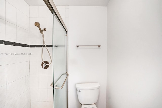 bathroom with toilet and a shower with shower door