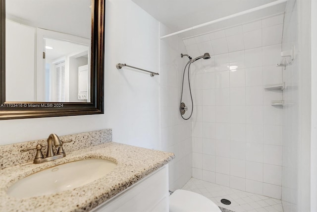 bathroom featuring tiled shower, vanity, and toilet