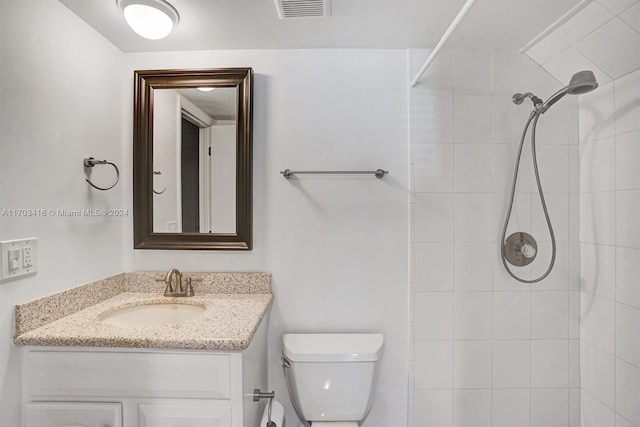 bathroom with vanity, toilet, and tiled shower