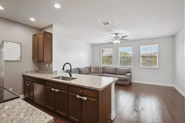 kitchen featuring a peninsula, light stone counters, open floor plan, and a sink