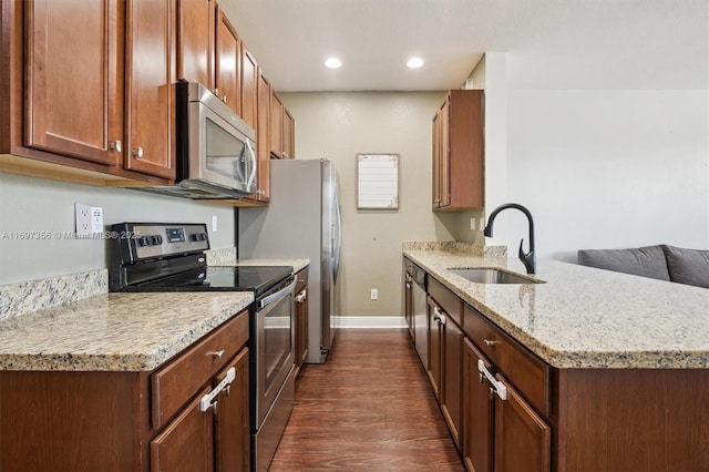 kitchen with dark wood-style floors, appliances with stainless steel finishes, a sink, light stone countertops, and baseboards