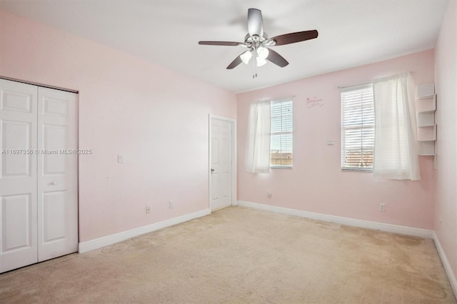 unfurnished bedroom with a closet, light carpet, ceiling fan, and baseboards