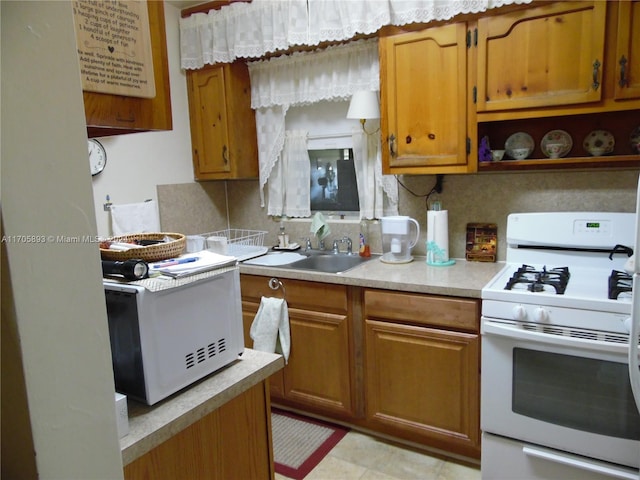 kitchen featuring decorative backsplash, sink, and white gas range oven