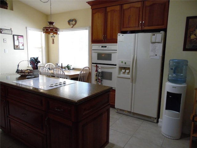 kitchen featuring light tile patterned floors, white appliances, and a kitchen island