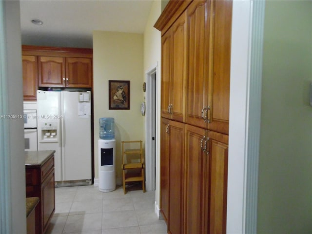 kitchen featuring light tile patterned flooring and white refrigerator with ice dispenser