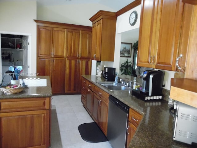 kitchen with stainless steel dishwasher, dark stone countertops, light tile patterned floors, and sink