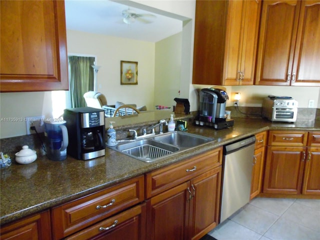 kitchen featuring ceiling fan, sink, light tile patterned floors, dark stone countertops, and dishwasher