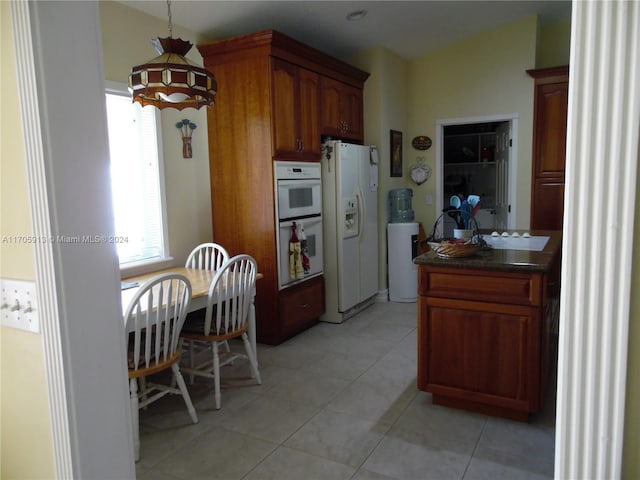 kitchen with light tile patterned floors, white appliances, and decorative light fixtures