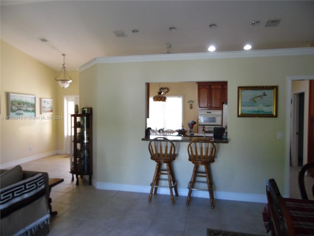 kitchen featuring a kitchen bar, oven, decorative light fixtures, and ornamental molding