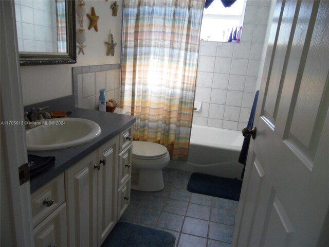 full bathroom with tile patterned floors, vanity, toilet, and shower / bath combo with shower curtain