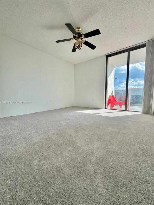 spare room featuring ceiling fan, expansive windows, a textured ceiling, and carpet flooring