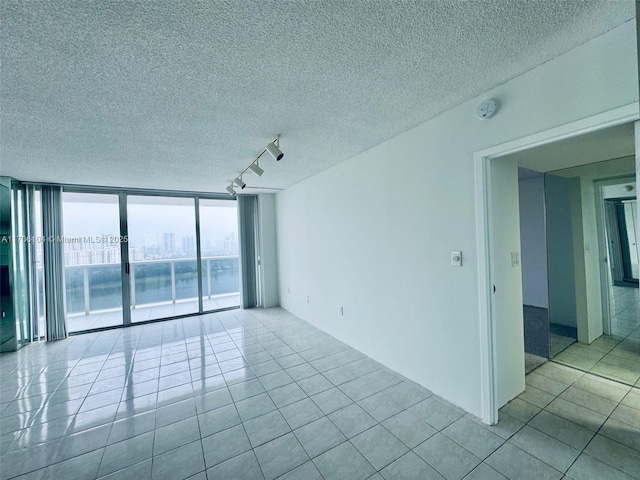 tiled empty room with a wall of windows and track lighting