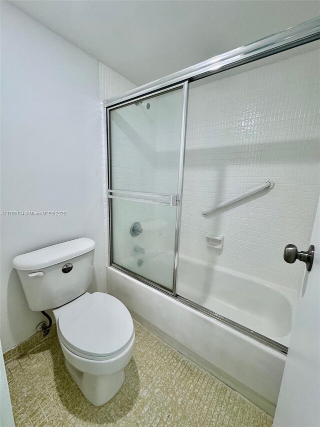 bathroom with combined bath / shower with glass door and toilet