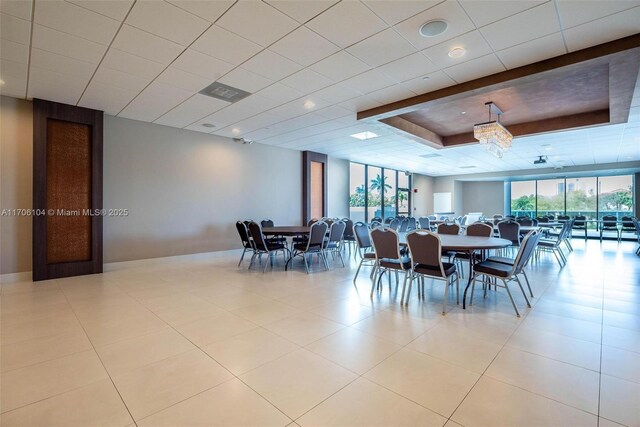 tiled dining space featuring a raised ceiling and a wealth of natural light