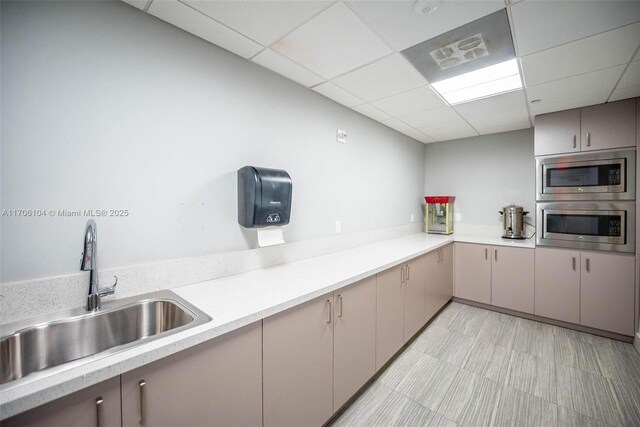 kitchen with a paneled ceiling, sink, stainless steel microwave, and oven