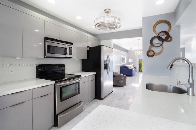 kitchen with gray cabinets, sink, decorative light fixtures, and appliances with stainless steel finishes