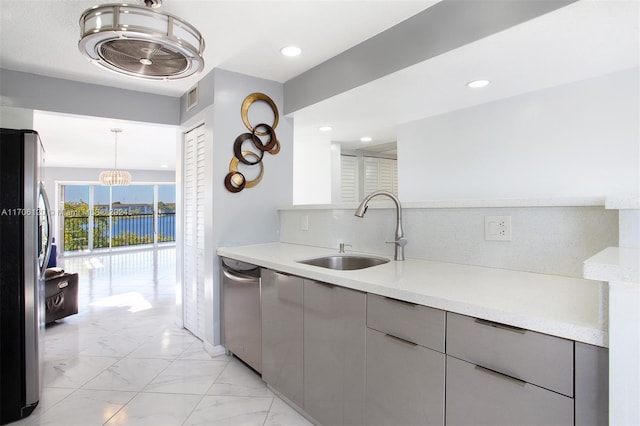 kitchen featuring a water view, sink, gray cabinets, decorative light fixtures, and stainless steel appliances