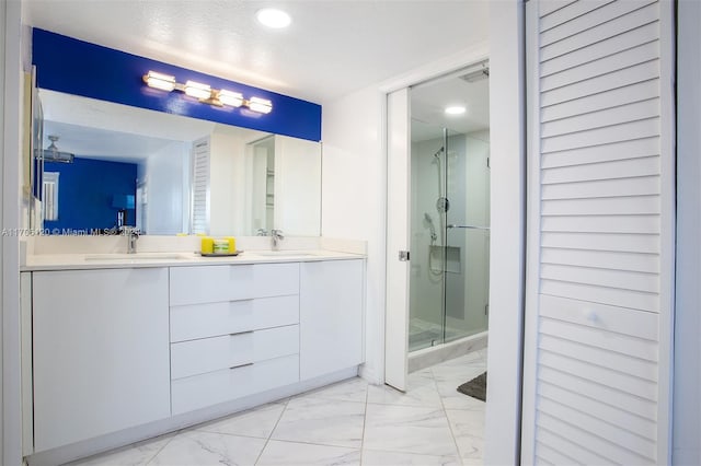 bathroom featuring a shower with door, vanity, and a textured ceiling